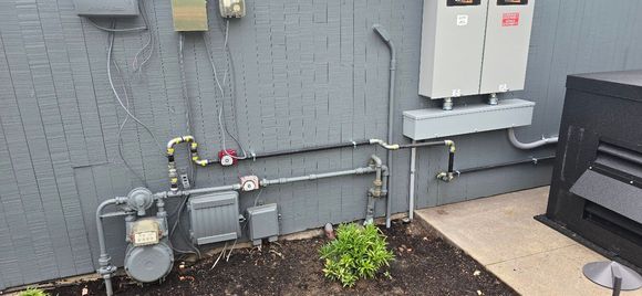 A water heater is sitting in a room next to a furnace.