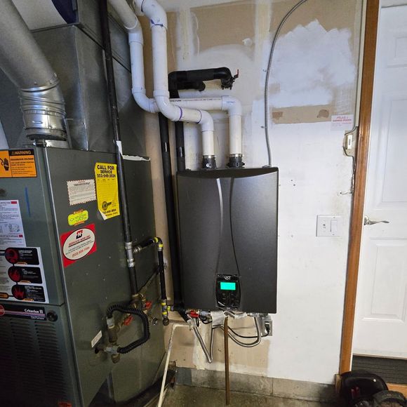 An air conditioner is sitting in a garage next to a broom.