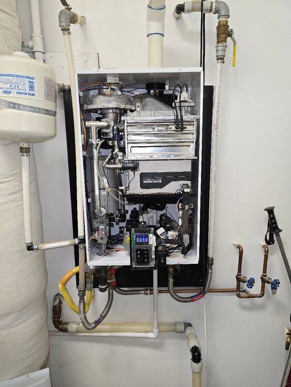 A man is working on a water heater in a room.