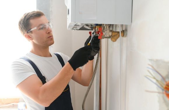 A man is working on a water heater in a room.