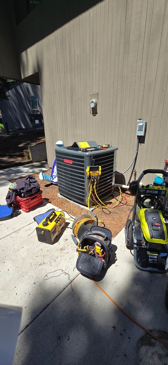 An air conditioner is sitting in a garage next to a broom.