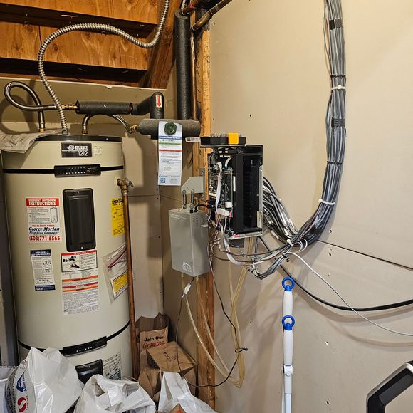 An air conditioner is sitting in a garage next to a broom.