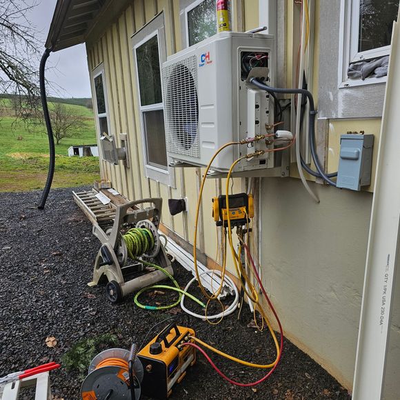 An air conditioner is being installed on the side of a house.