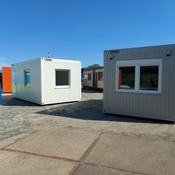 Een wit gebouw met een raam staat naast een grijs gebouw met een raam