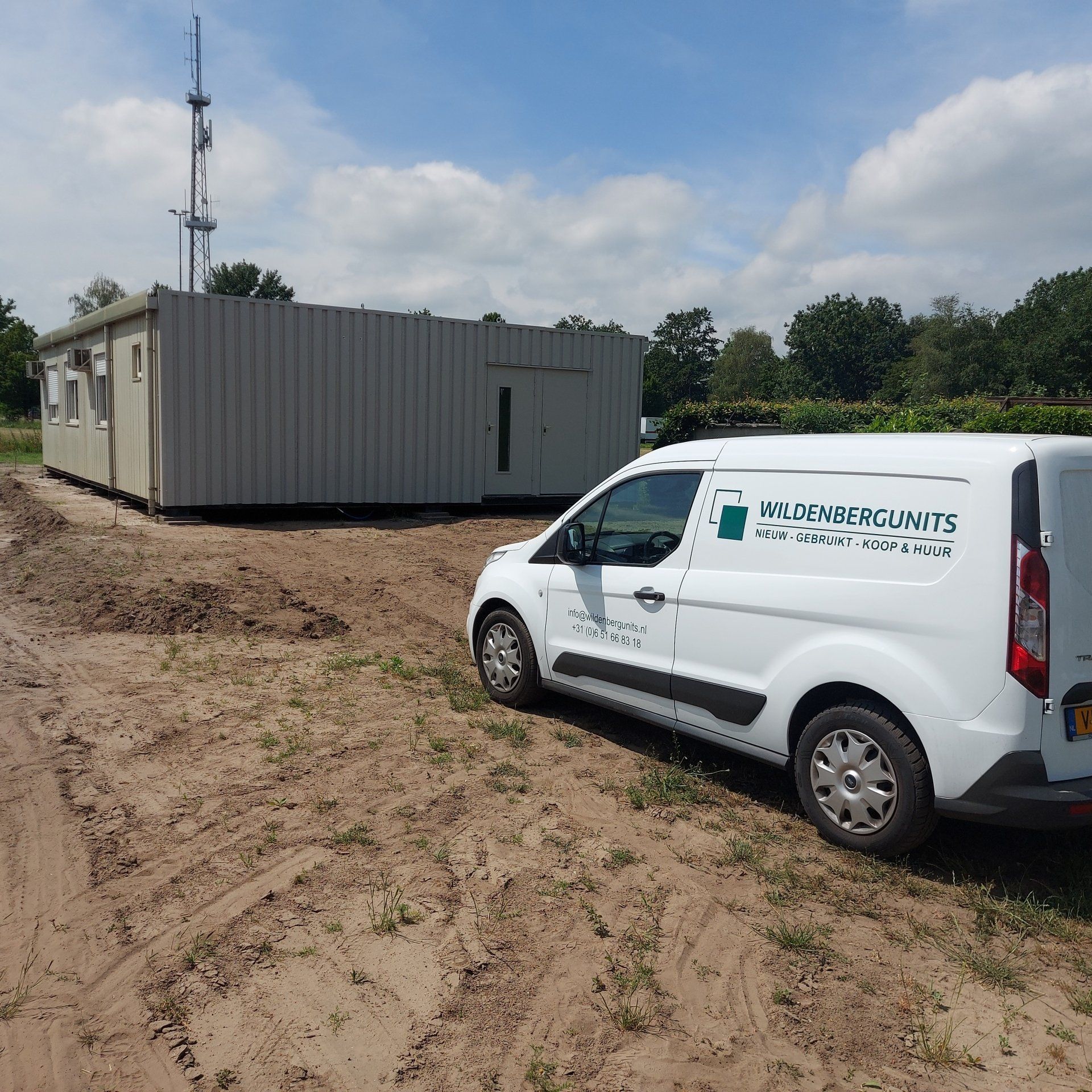 Een grijs gebouw met rode randen en een bordje met daarop 'a'