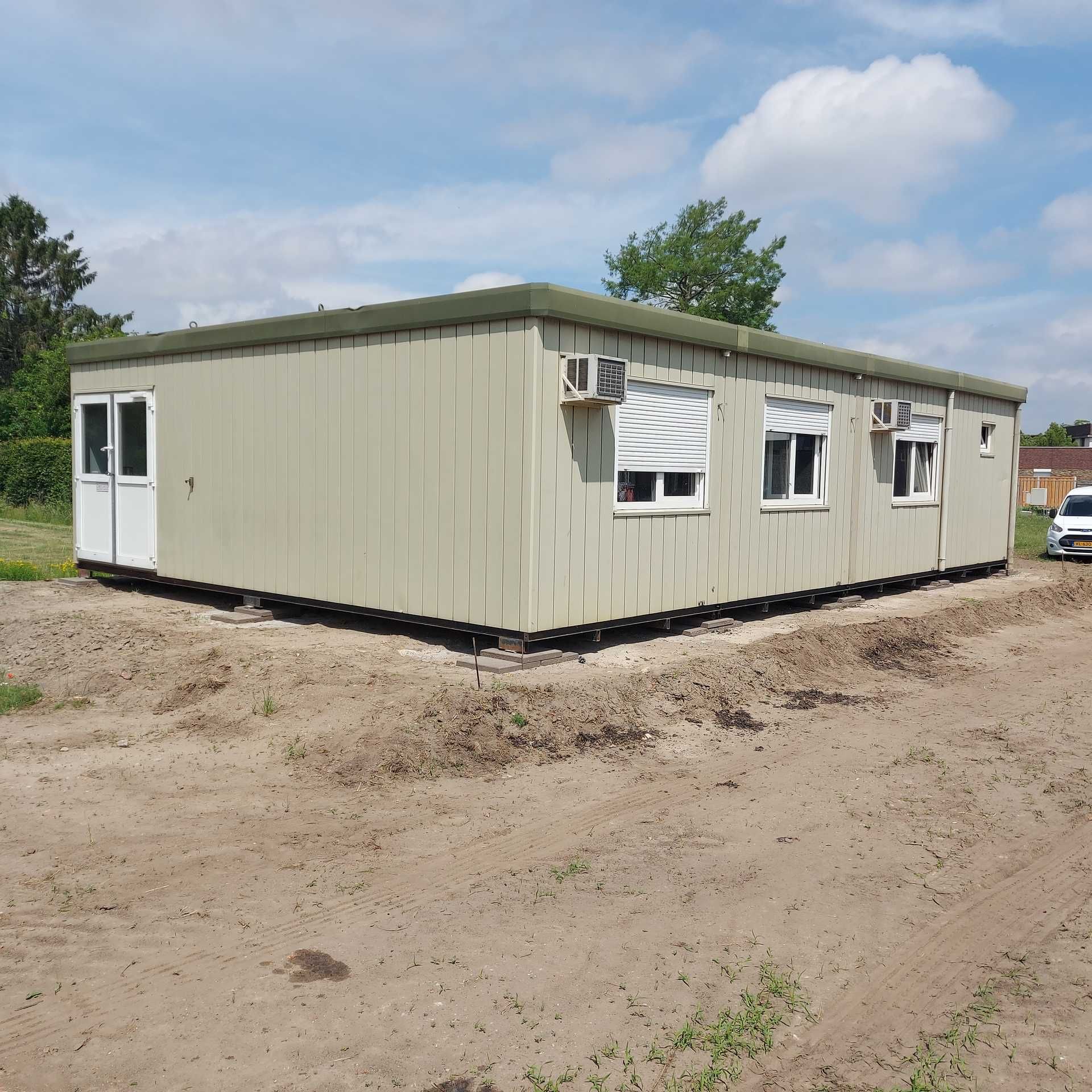 Een grijs gebouw met rode randen en een bordje met daarop 'a'