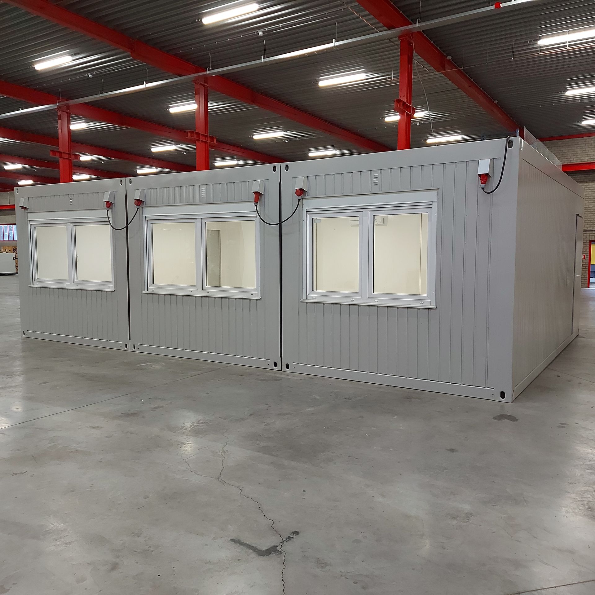Een grijs gebouw met rode randen en een bordje met daarop 'a'