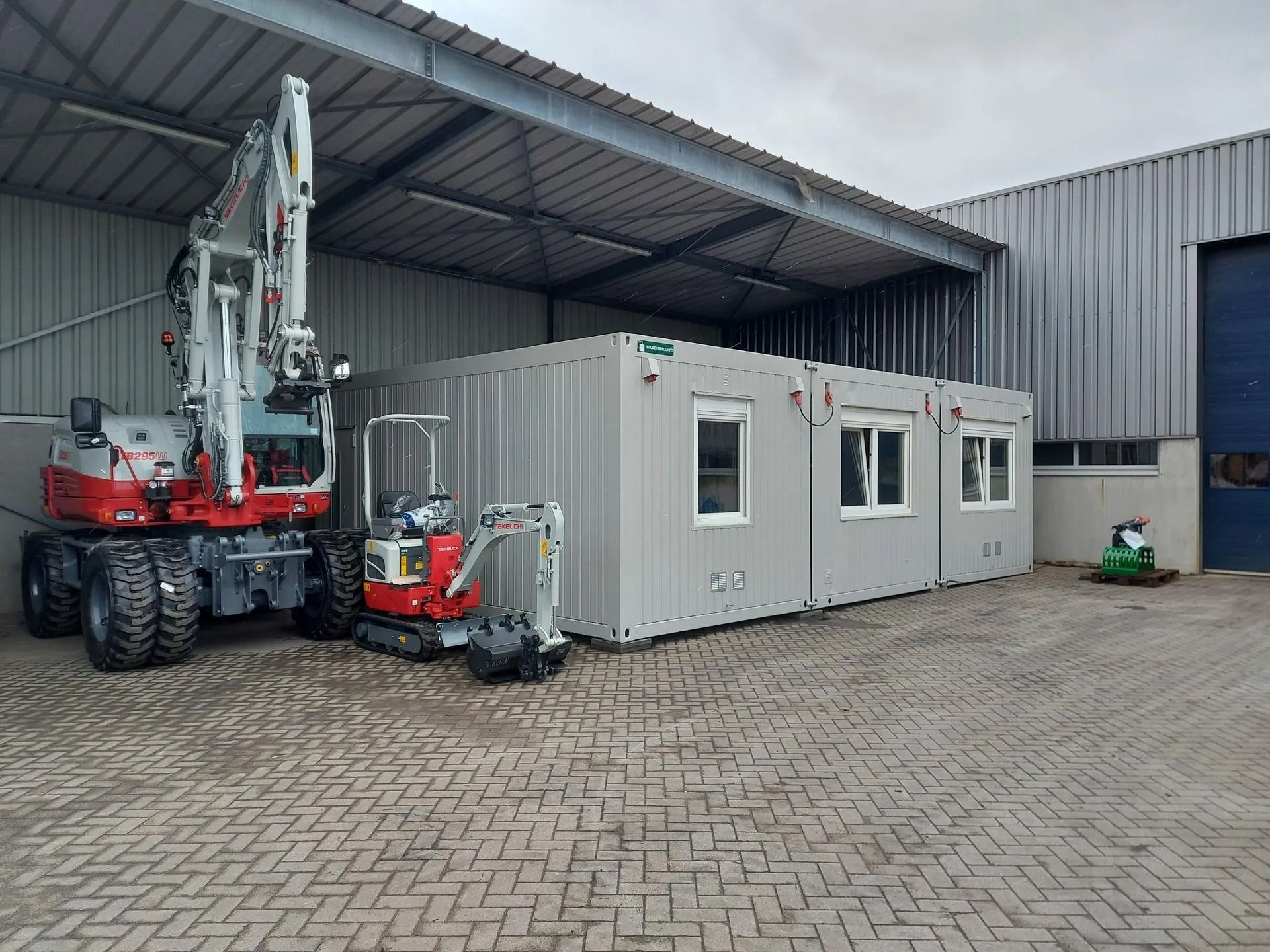 Er staan een rij containers voor een gebouw.