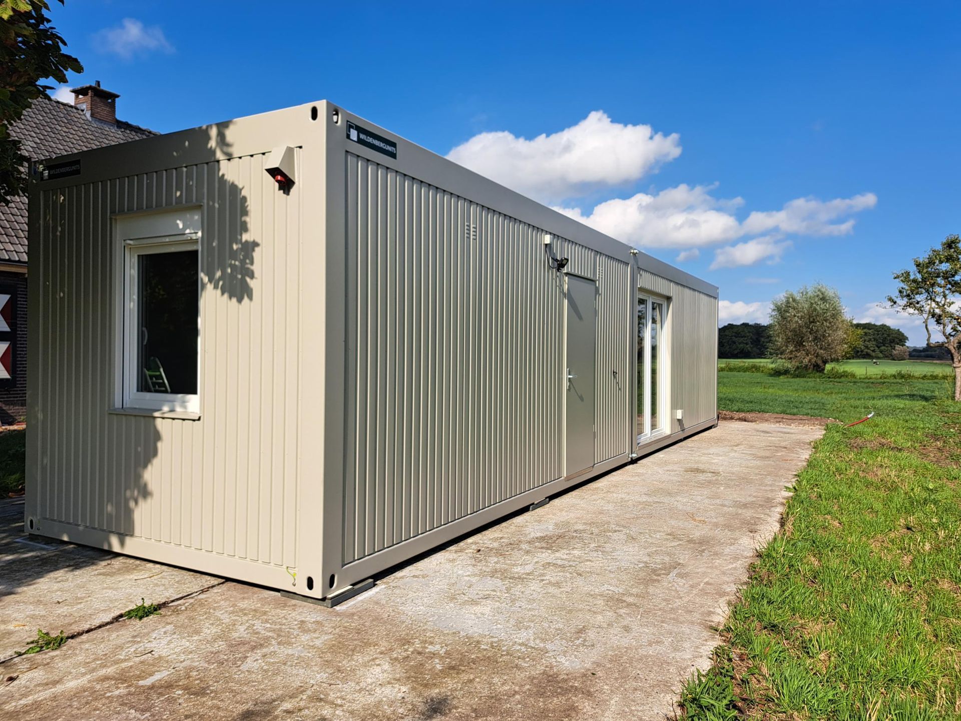Midden in een grasveld staat een containerhuis.