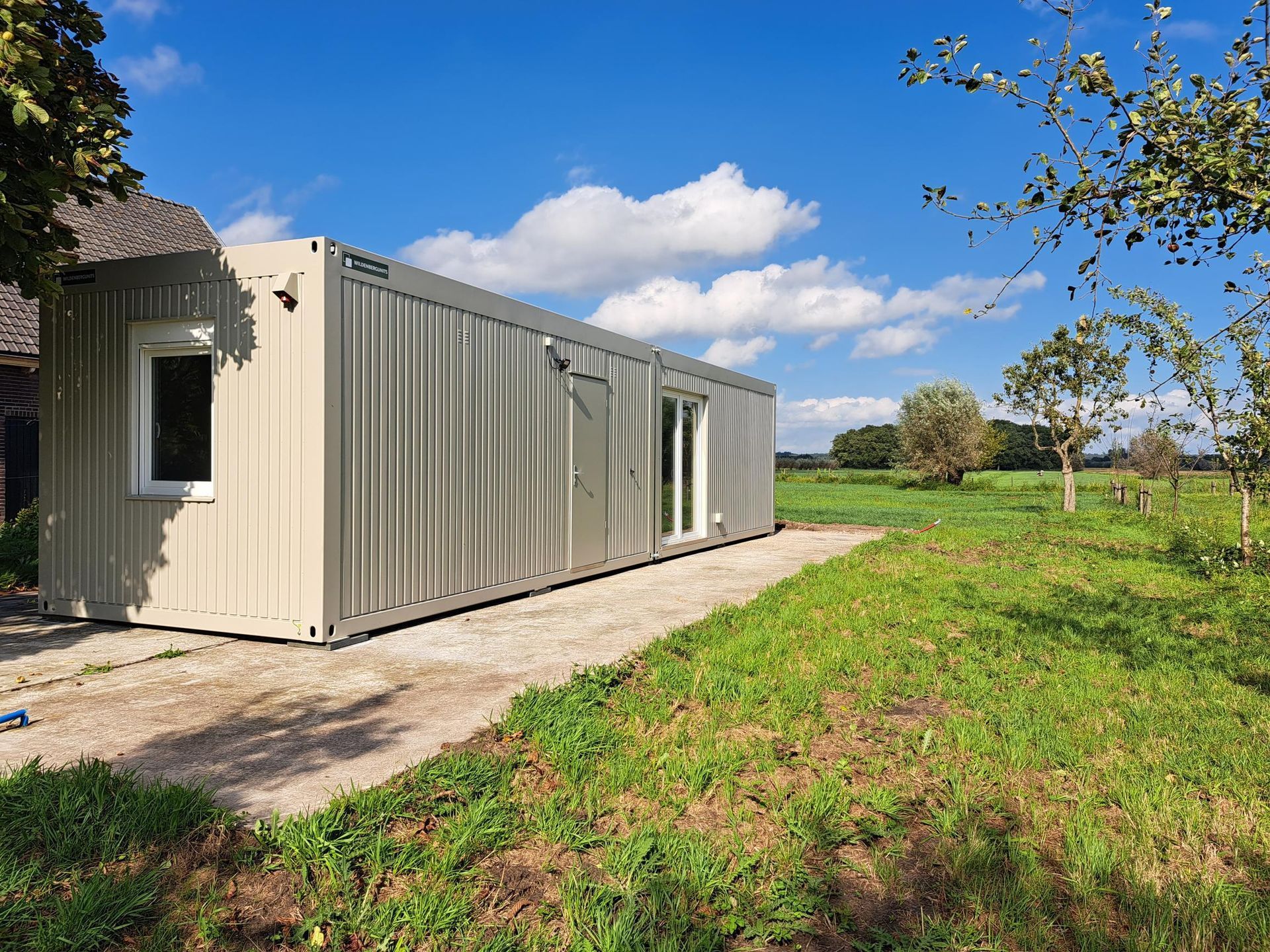 Een zeecontainer staat midden in een grasveld.