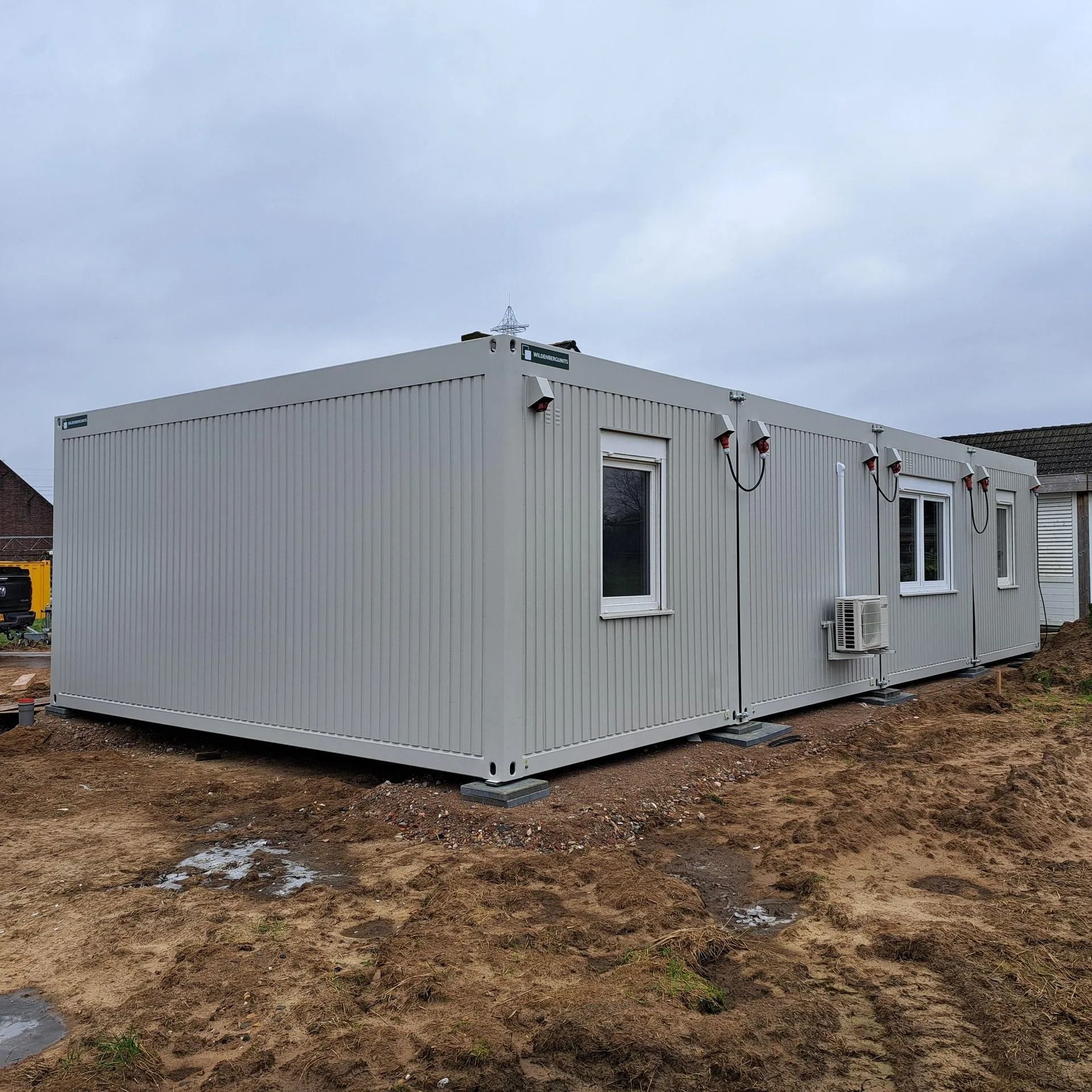 Een groot wit gebouw staat midden op een zandveld.