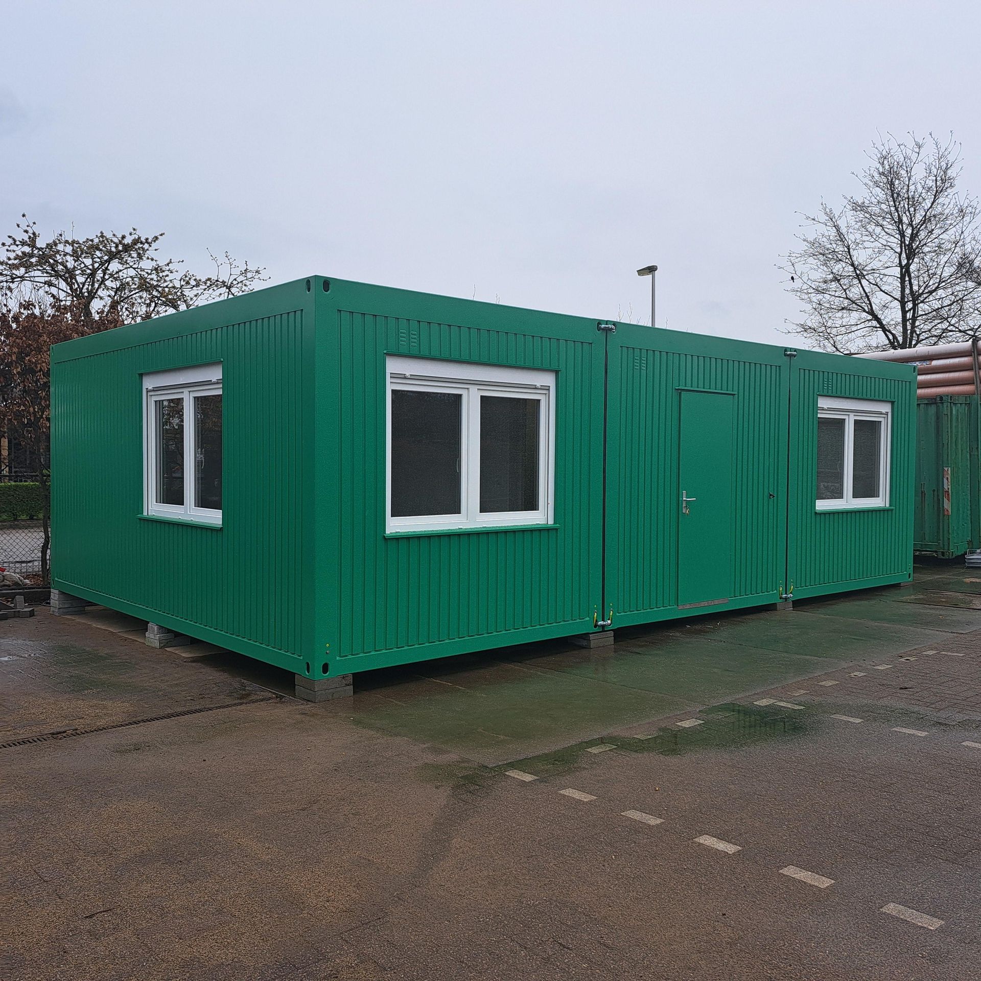 Een grijs gebouw met rode randen en een bordje met daarop 'a'