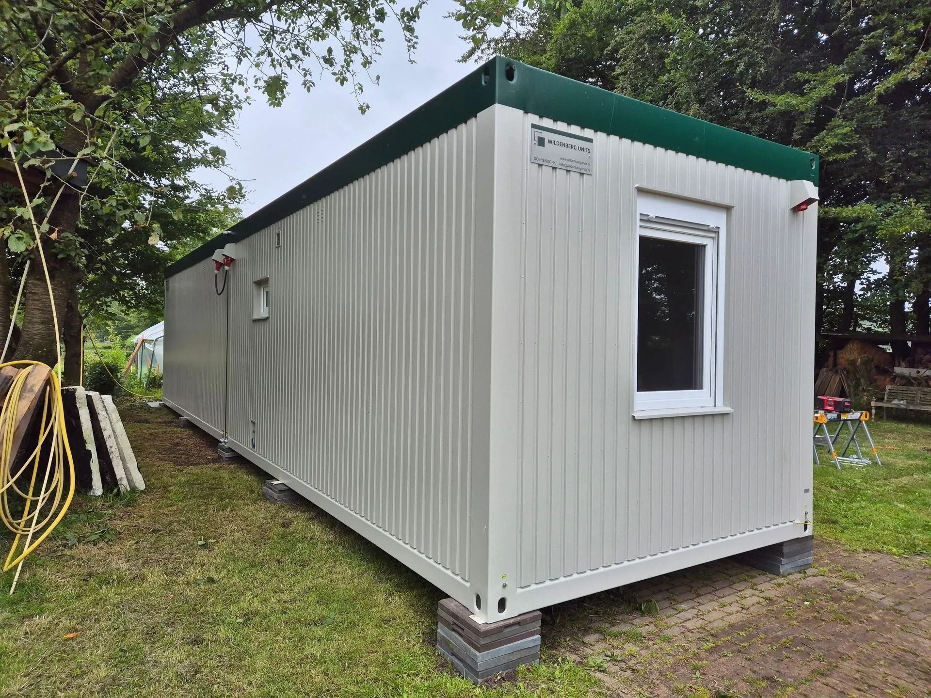 Een grijs gebouw met rode randen en een bordje met daarop 'a'