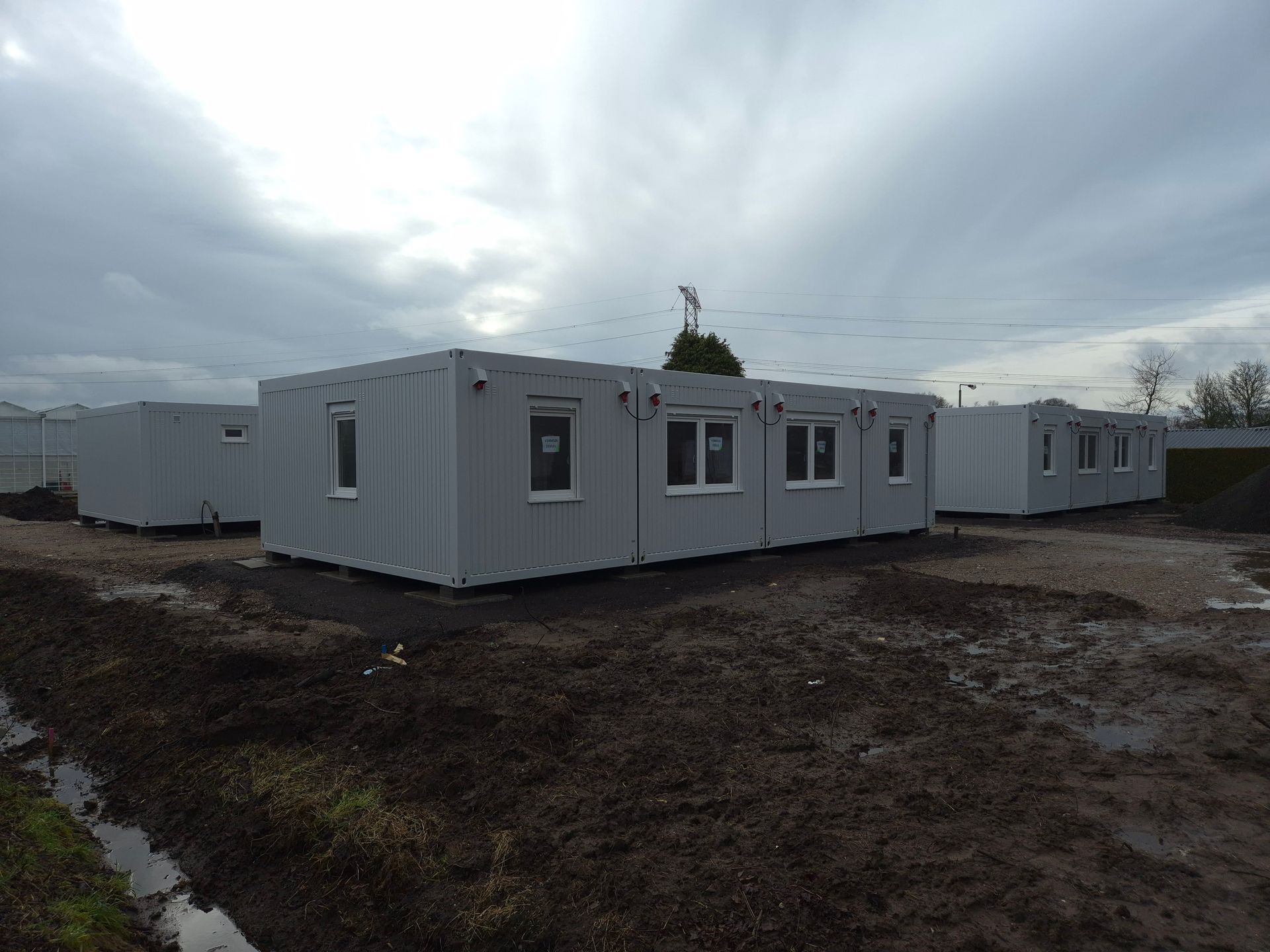 Een grijs gebouw met rode randen en een bordje met daarop 'a'