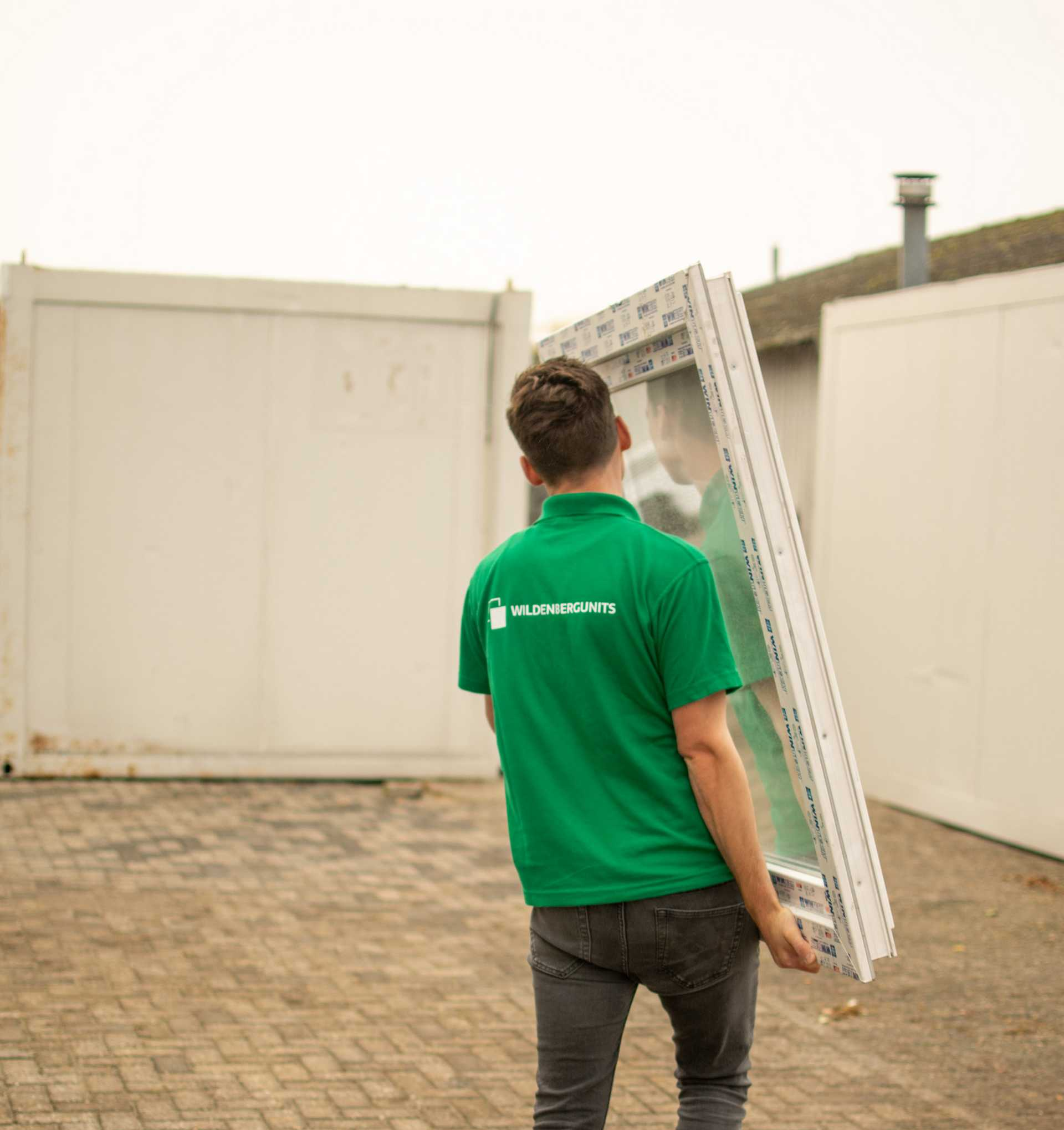 Een man in een groen shirt draagt een groot raam