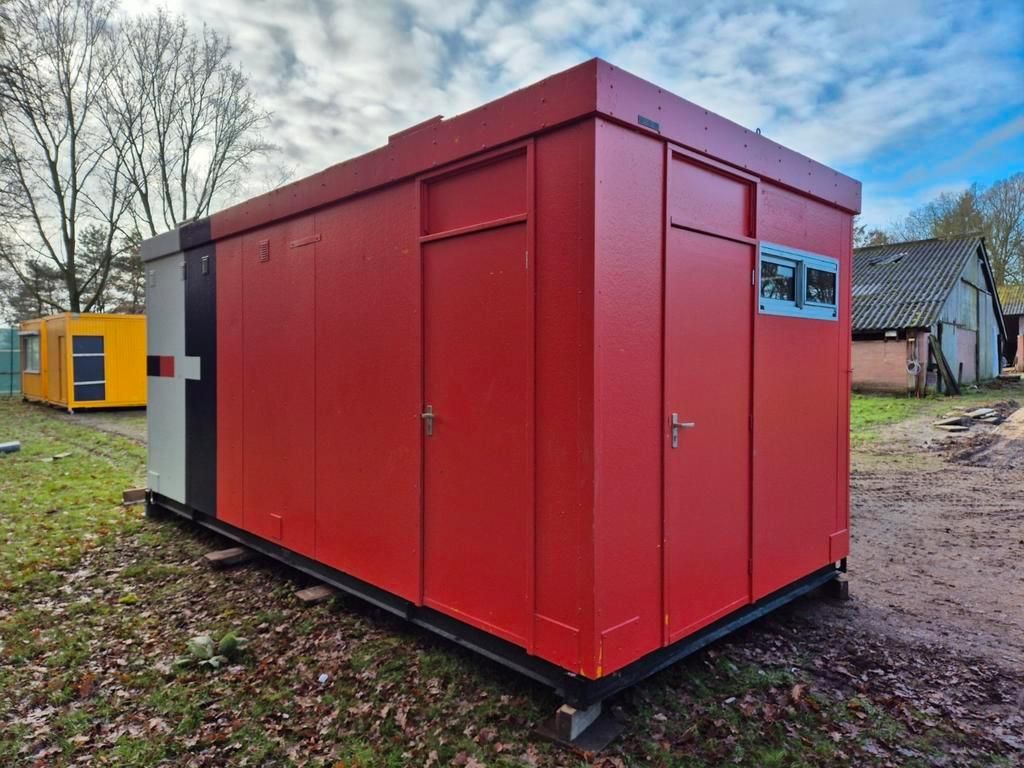 Een rood gebouw staat midden in een veld.