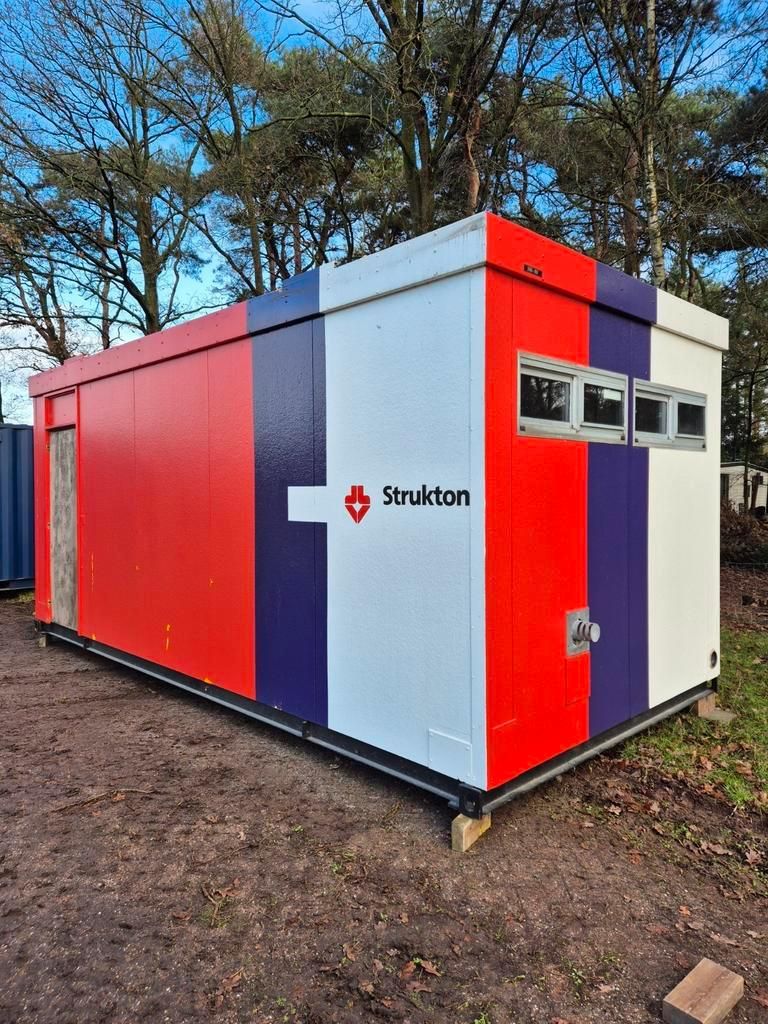 Een rood, wit en paars gebouw staat midden in een veld.