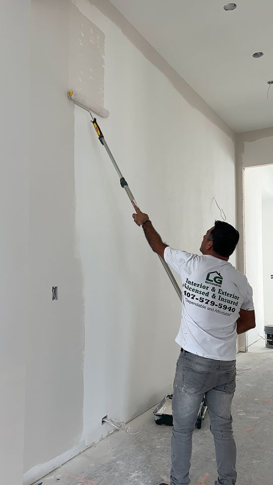 A man is painting a wall with a paint roller.
