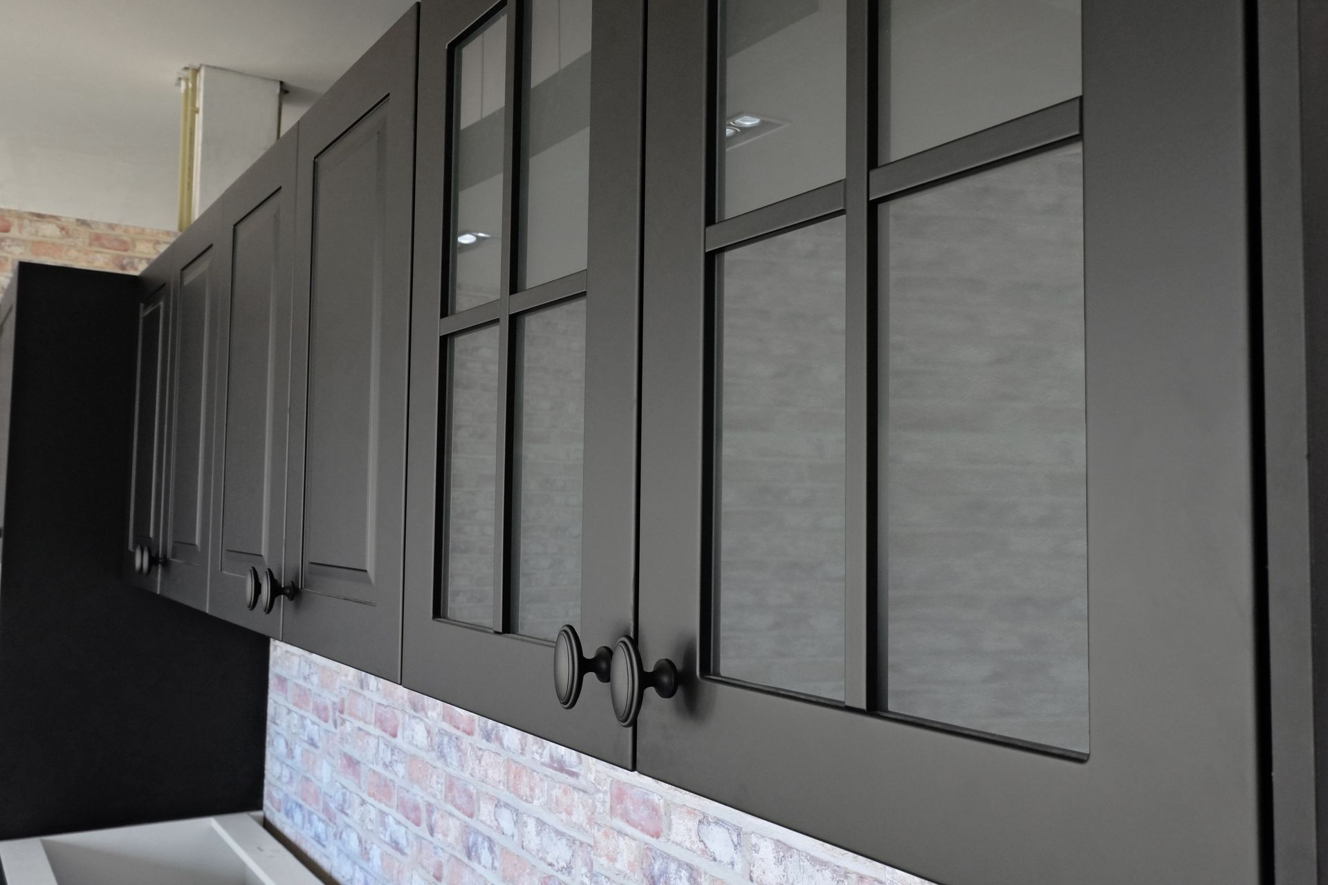 A kitchen with black cabinets and glass doors.
