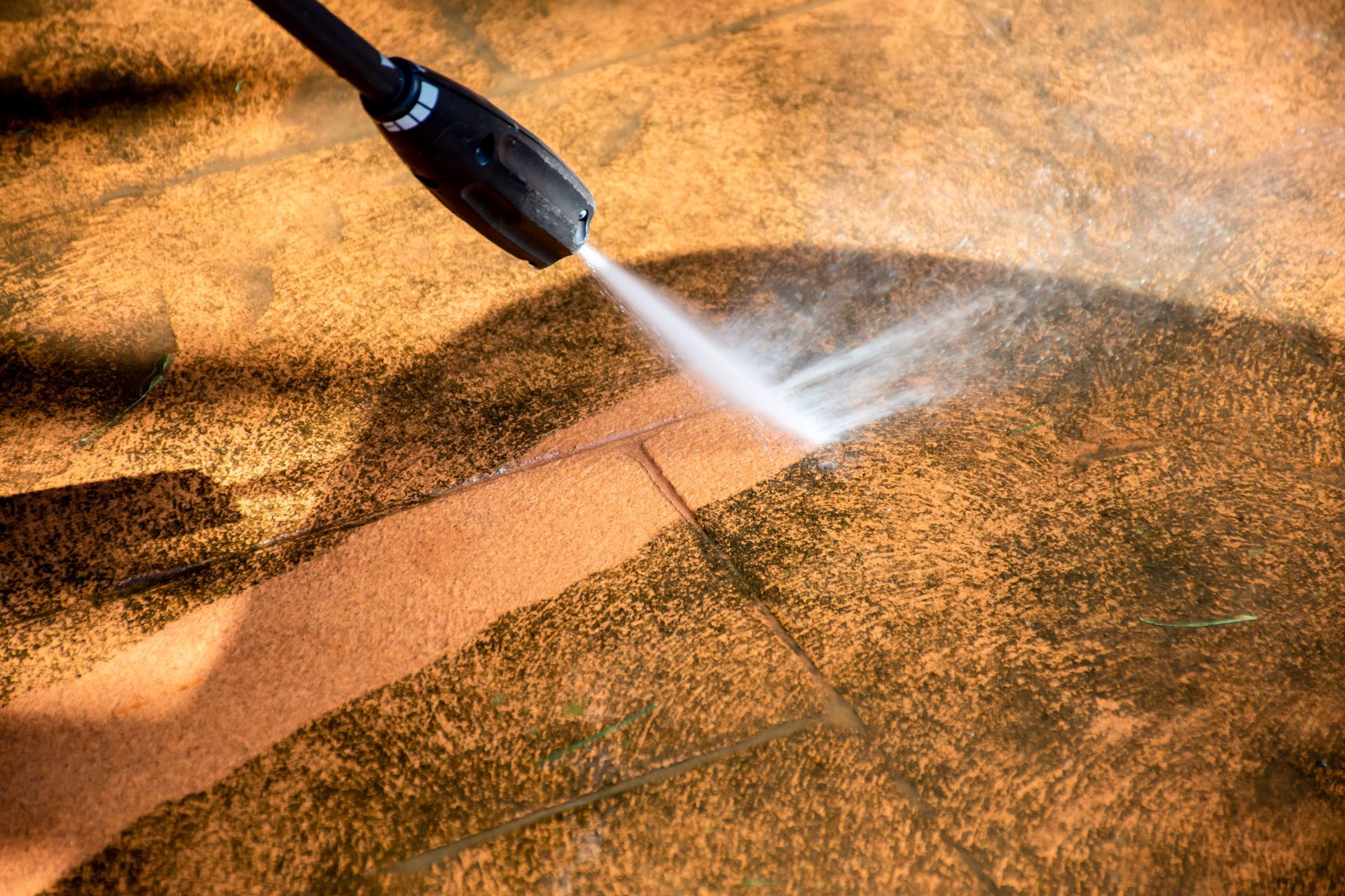 A person is using a high pressure washer to clean a concrete floor.