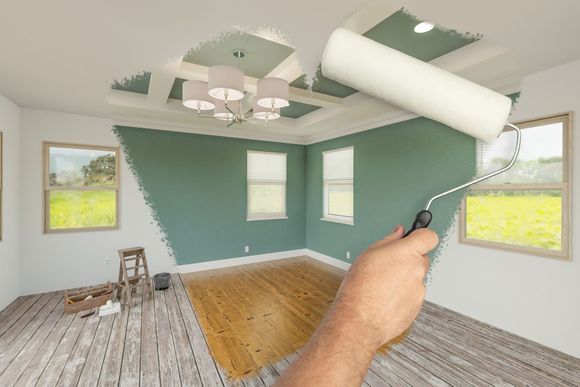 A man is painting a yellow wall in an empty room