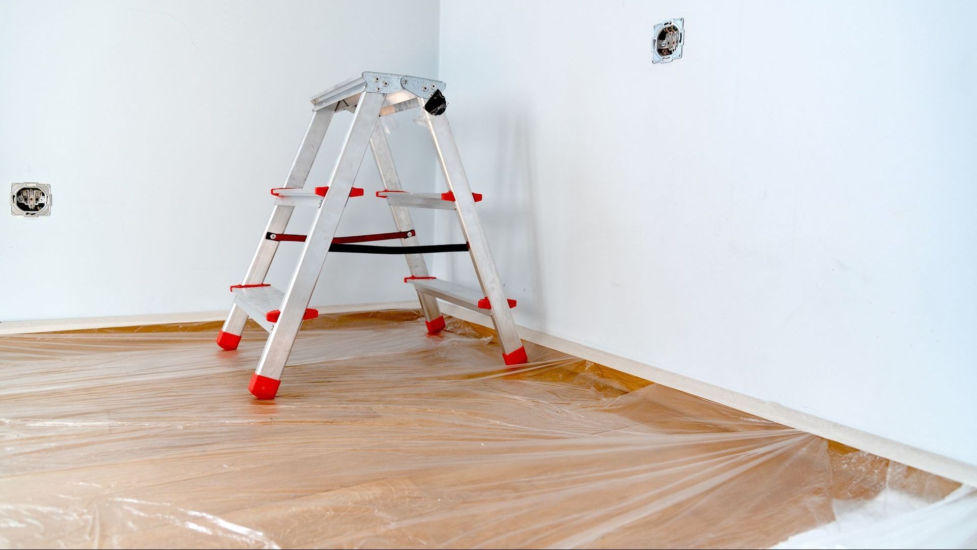 A ladder is sitting on top of a plastic sheet in a room.