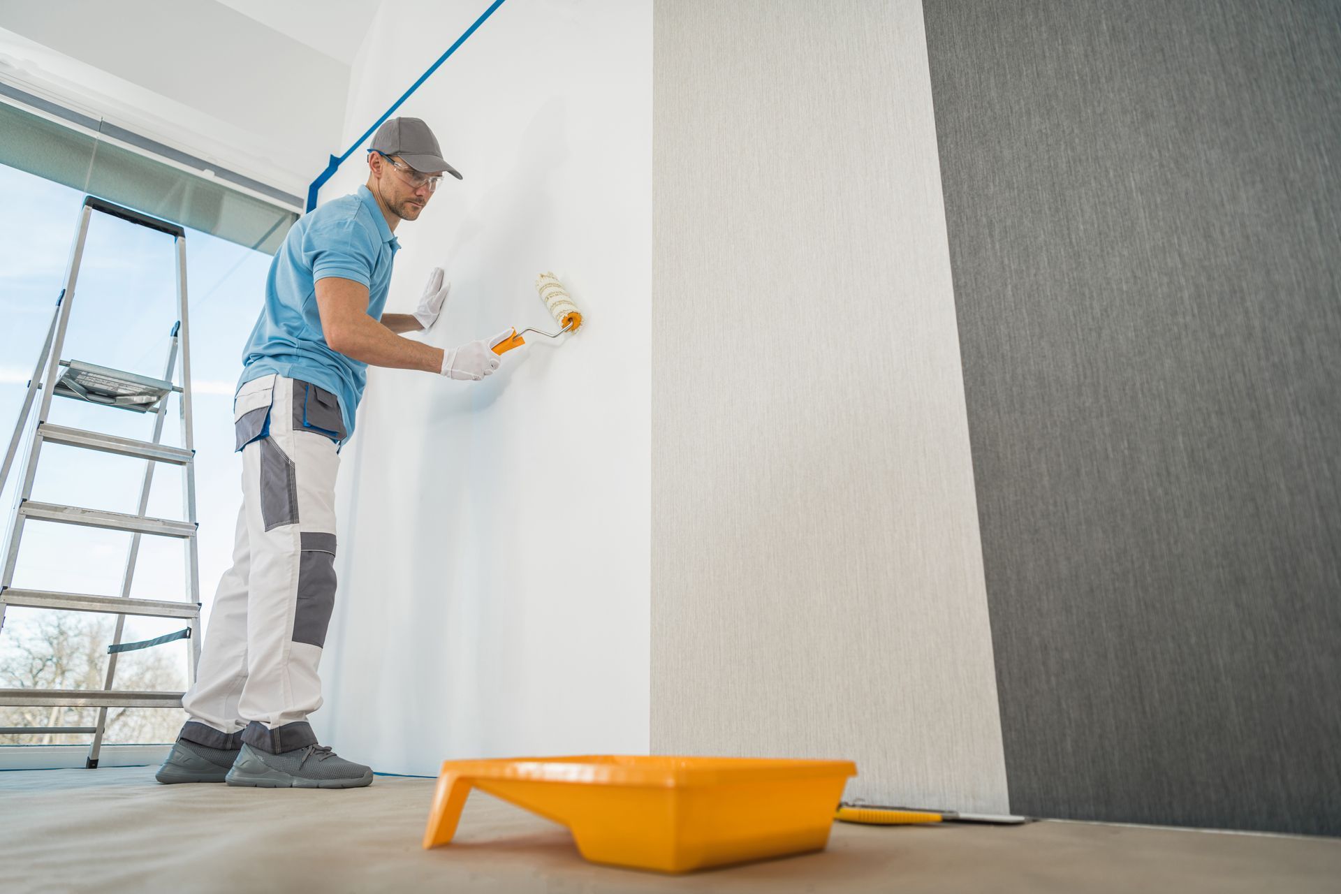 A man is painting a wall with a paint roller.