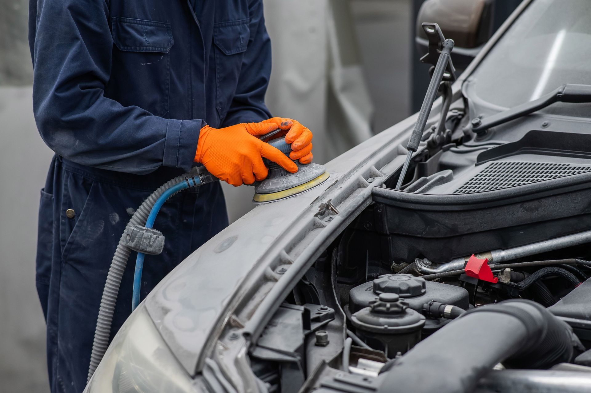 An auto body specialist sanding a repaired area on a vehicle.