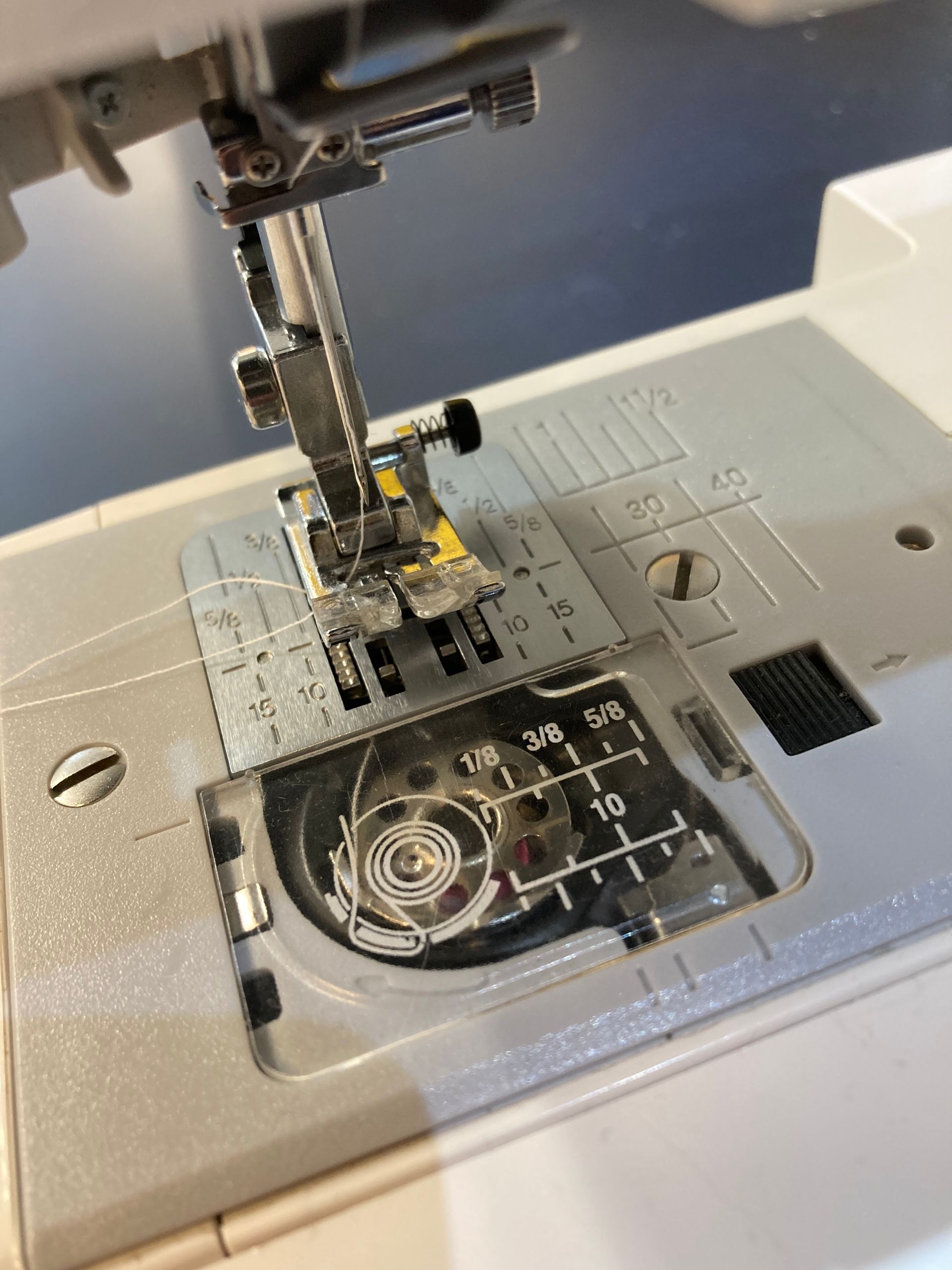 A sewing machine is stitching a piece of black fabric