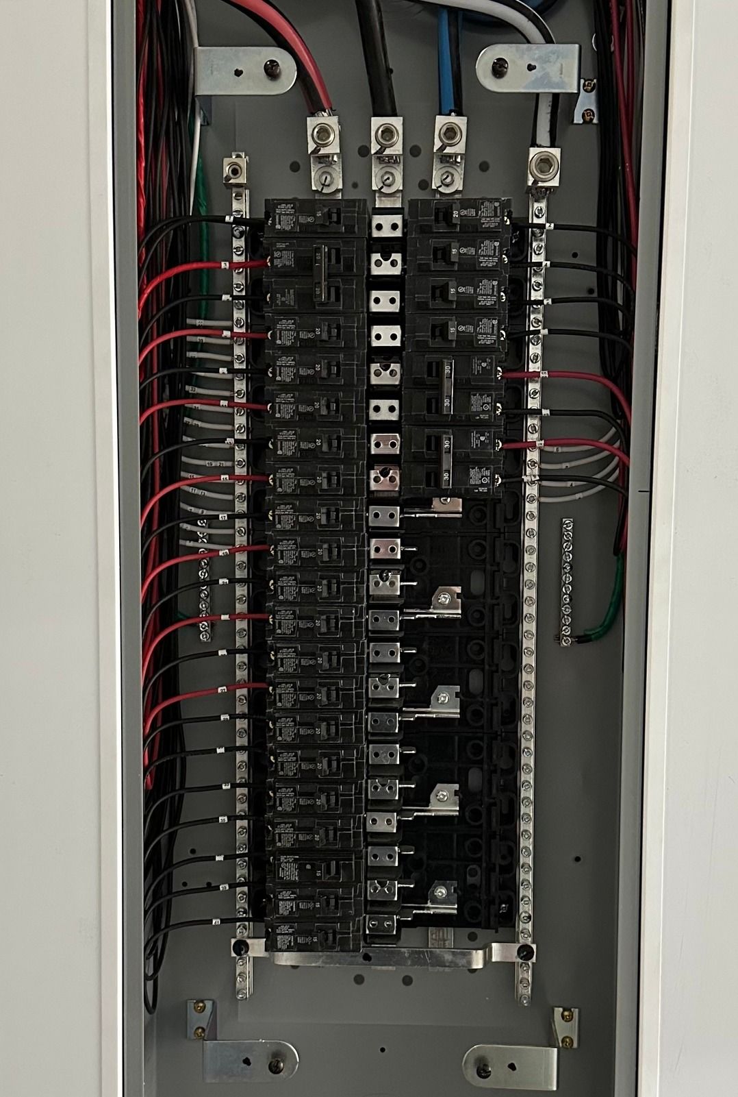 Un tableau électrique ouvert montrant plusieurs disjoncteurs avec des fils connectés aux barres omnibus.