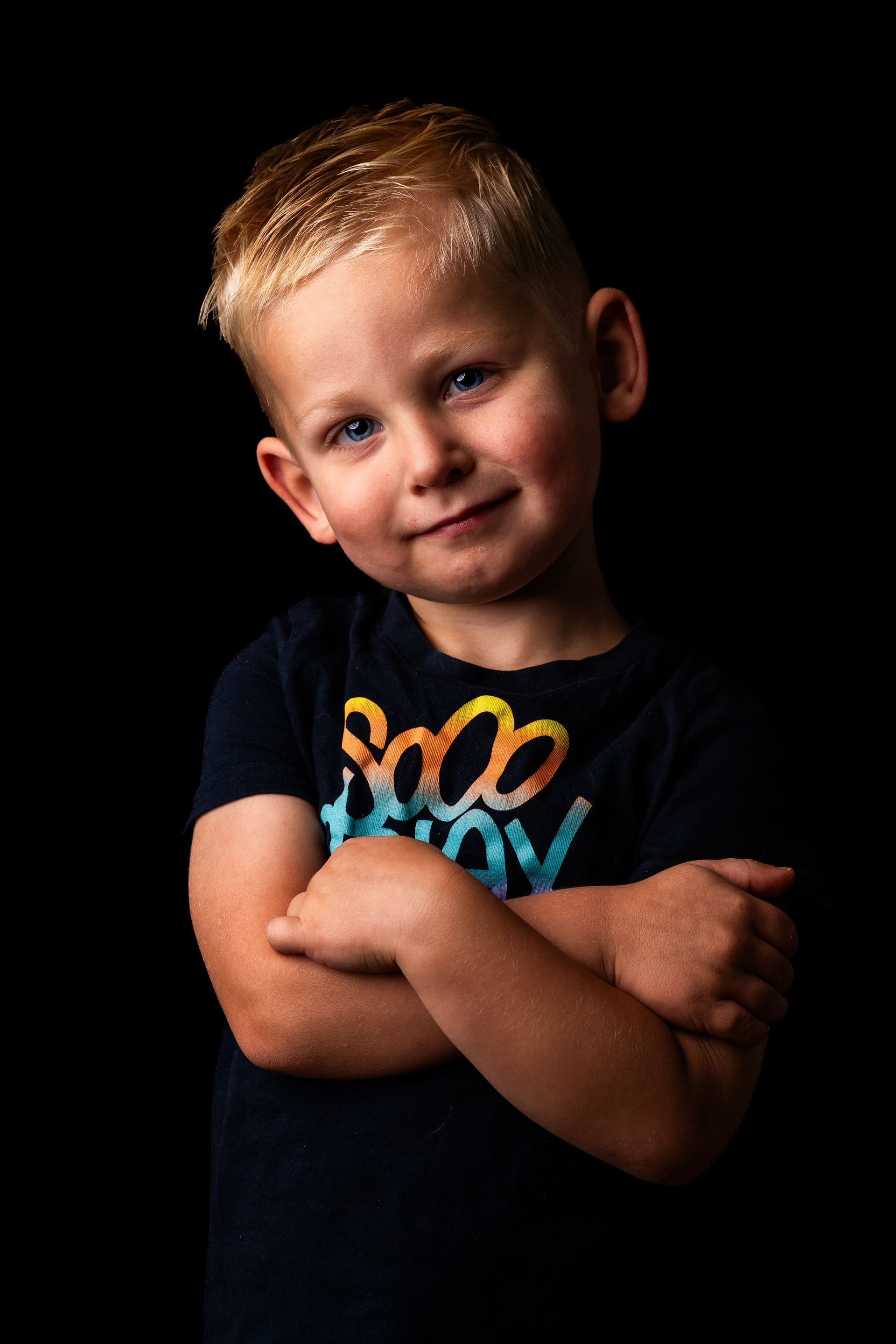Een jonge jongen met zijn armen over elkaar draagt ​​een zwart shirt.