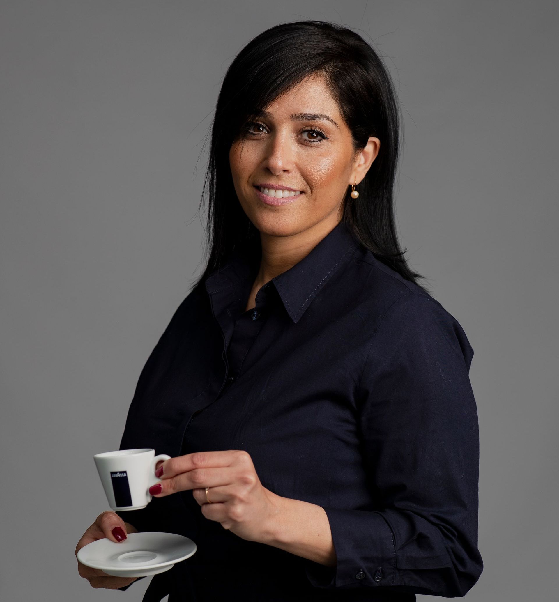 Een vrouw in een zwart shirt houdt een kopje koffie vast