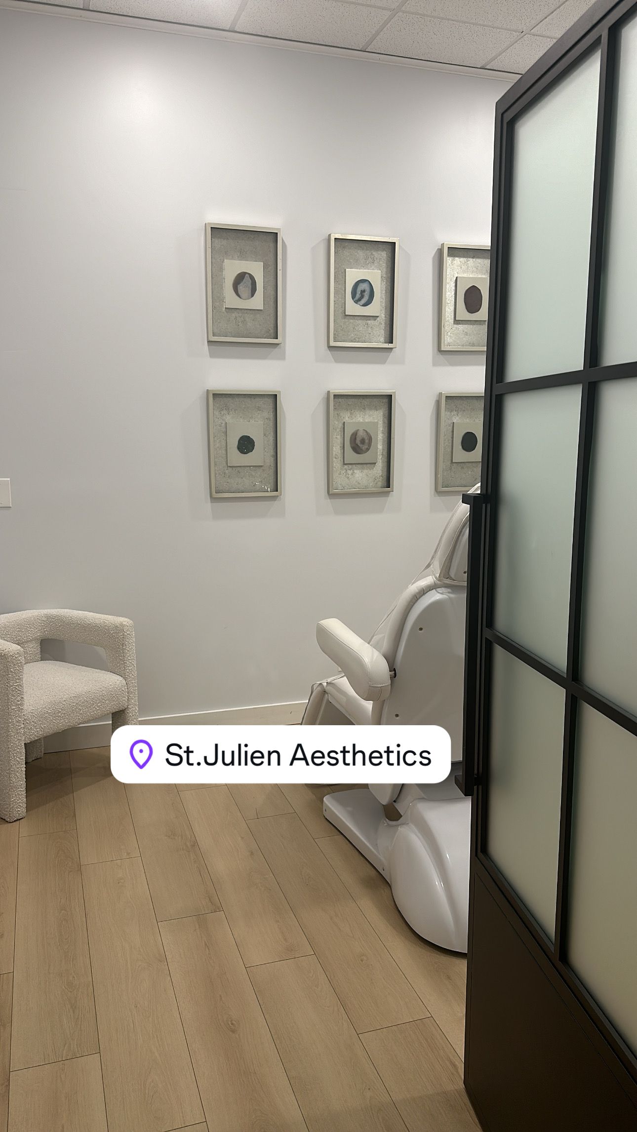 Interior of St. Louis Aesthetics with a white chair, art on the wall, and a medical chair.