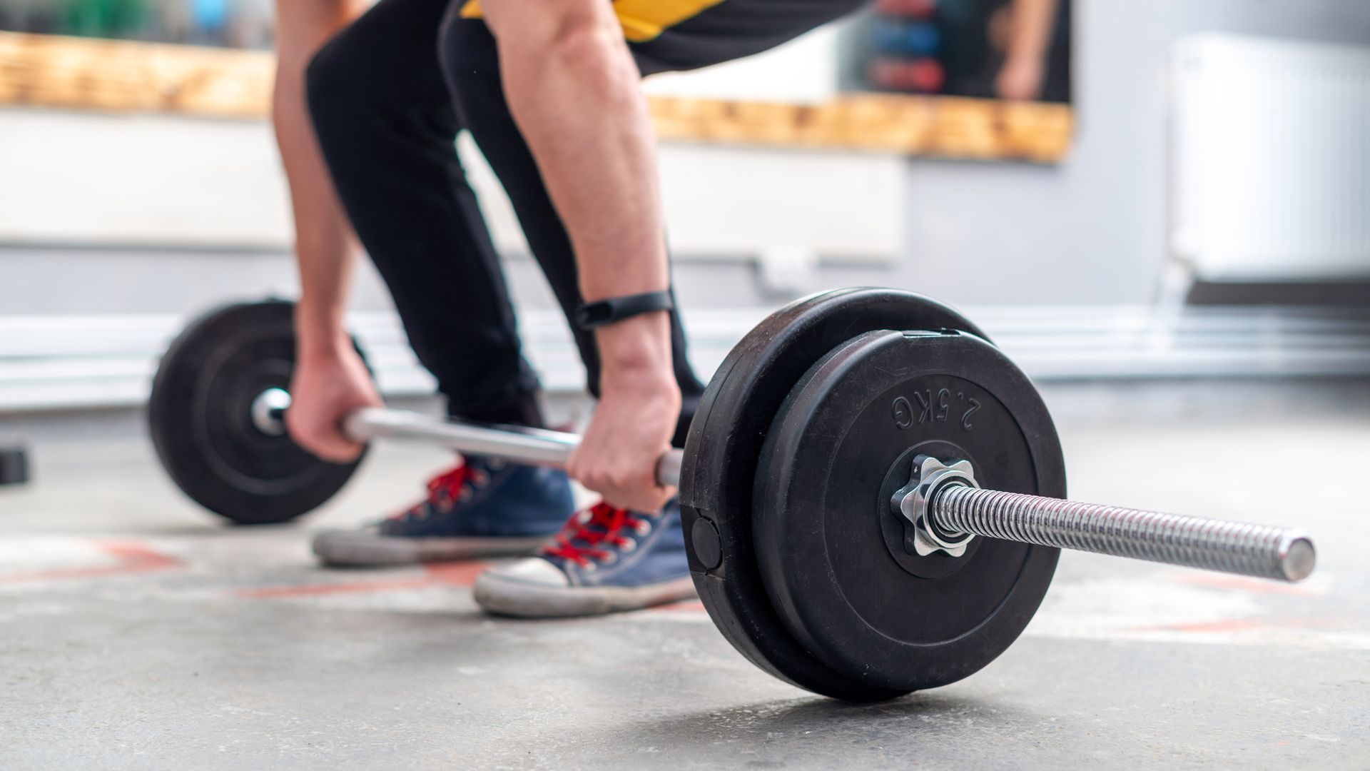 A man is lifting a barbell in a gym.