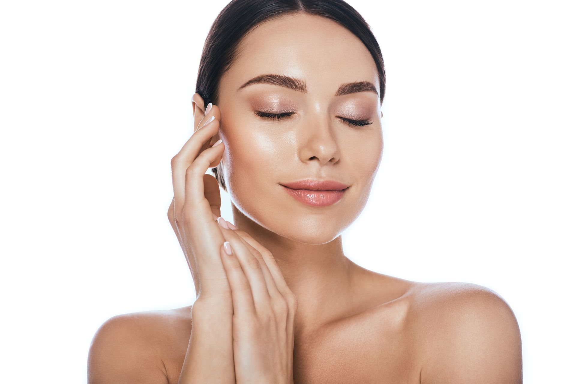 A woman is touching her face with her hands and smiling with her eyes closed.