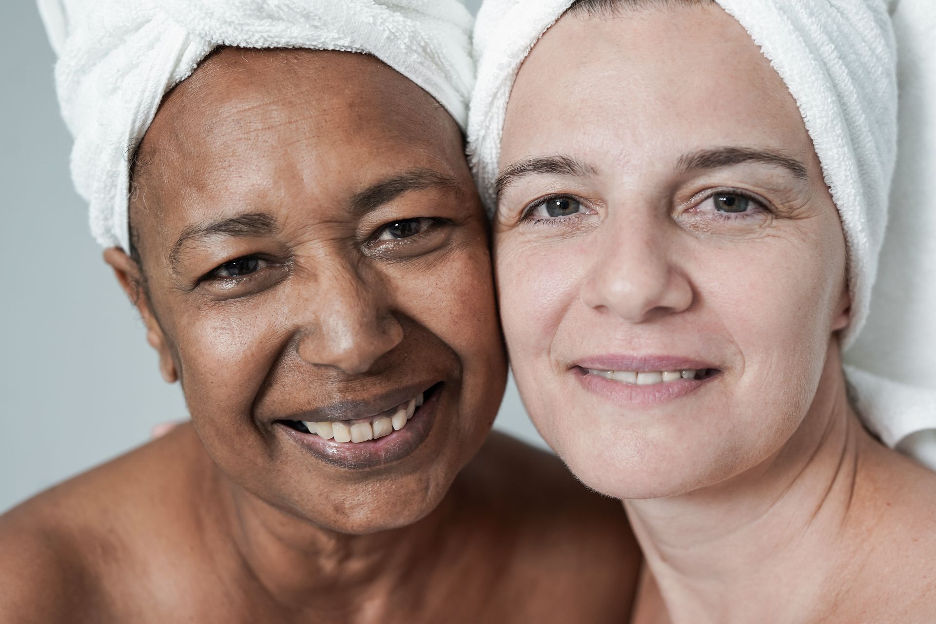 Two women with towels wrapped around their heads are smiling for the camera.