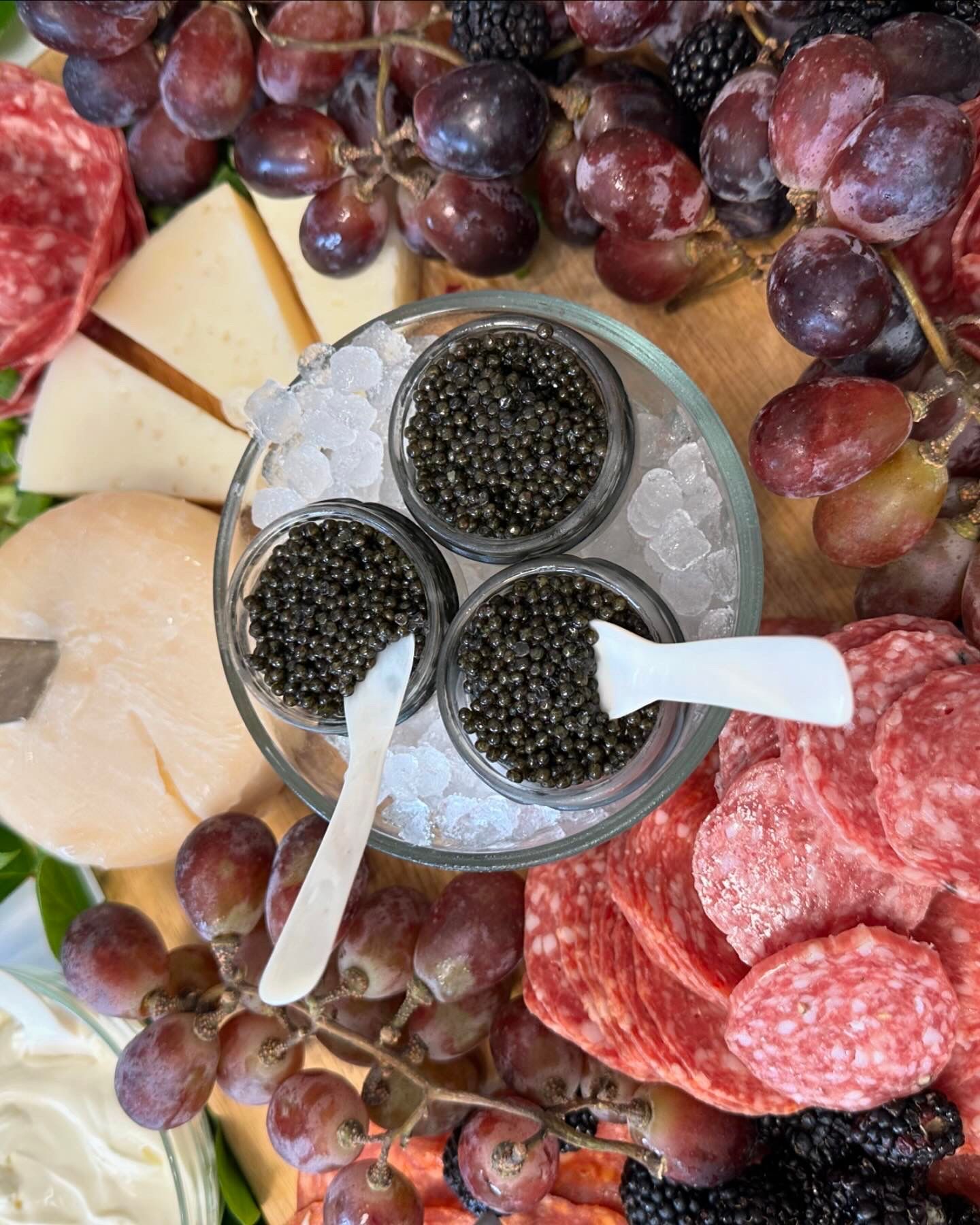 Charcuterie board with caviar, grapes, cheese, and salami.