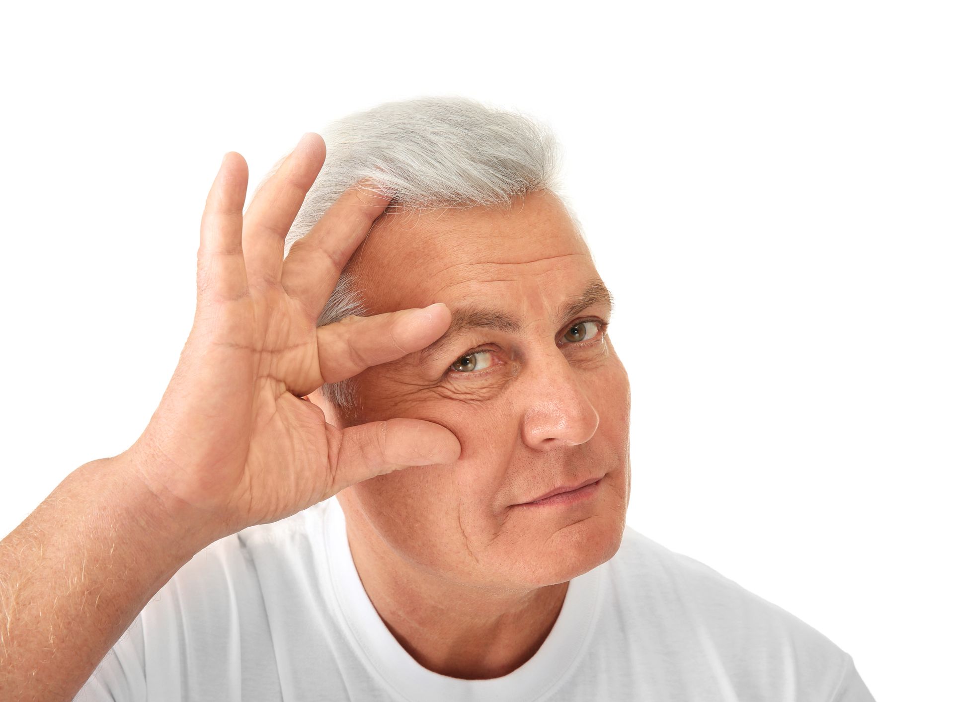 Mature man, gray hair, pulling skin near eye, looking at camera. White background.