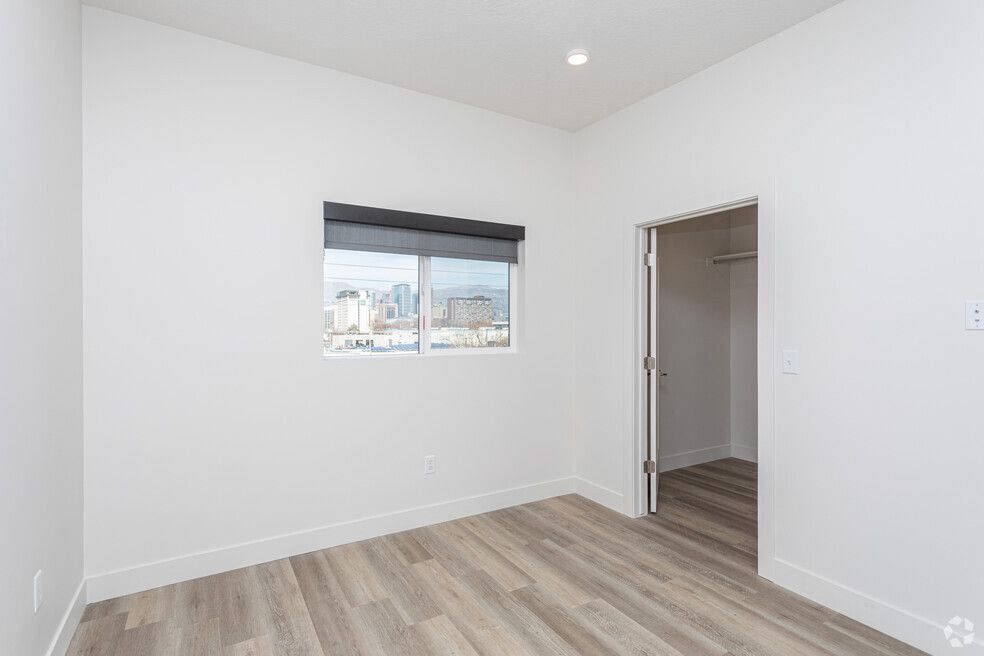 an empty bedroom with hardwood floors and a window .