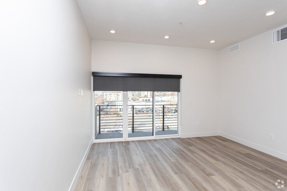 an empty living room with hardwood floors and sliding glass doors leading to a balcony .