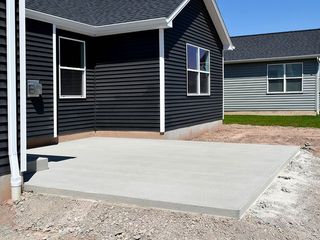 A concrete patio is being built in front of a house.