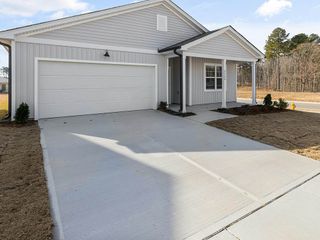 A white house with a garage and a driveway in front of it.