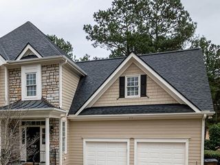 A large house with a black roof and white garage doors.