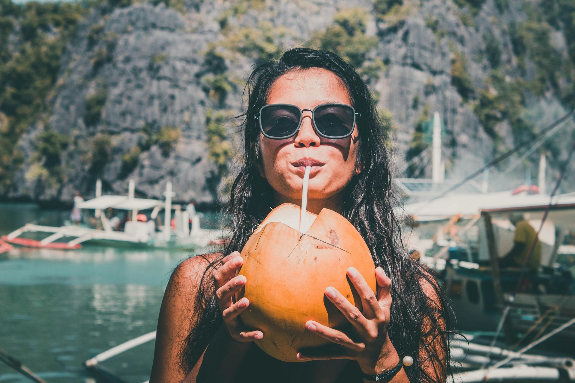 A woman is drinking coconut water through a straw.