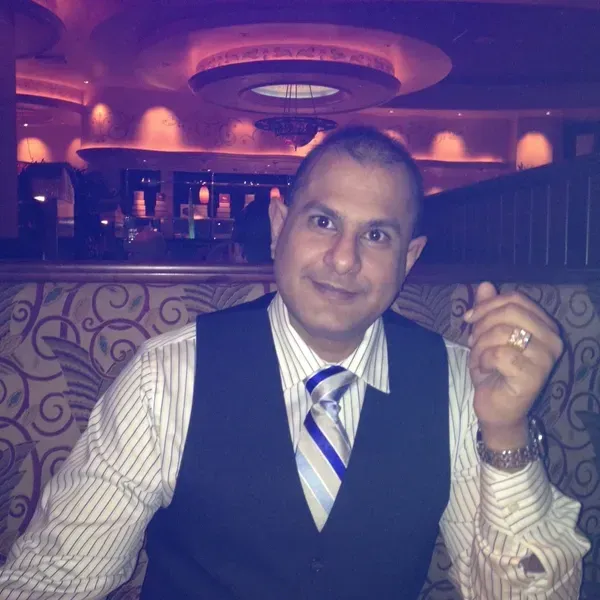 A man in a vest and tie is smiling for the camera