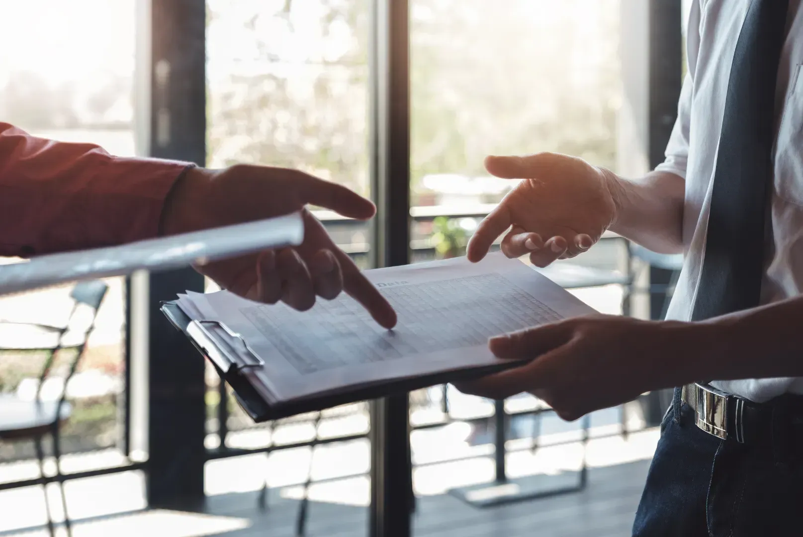 A man is pointing at a piece of paper while another man holds a clipboard.