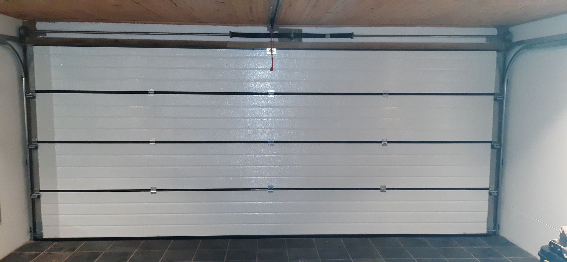 A closed white garage door with horizontal lines, inside a garage.
