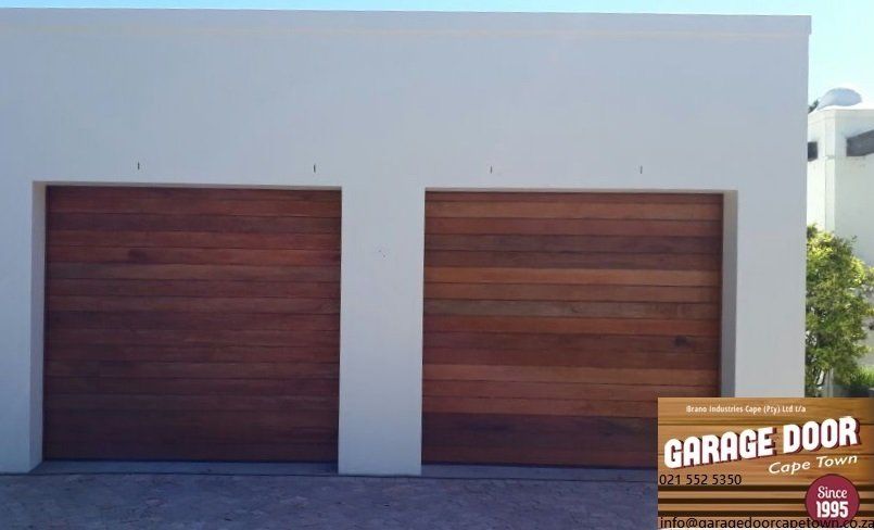 Two wooden garage doors on a white building with text
