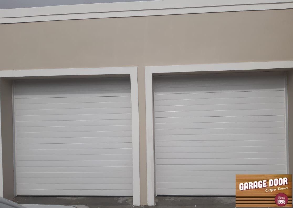 Two white garage doors with beige trim, exterior of a building.