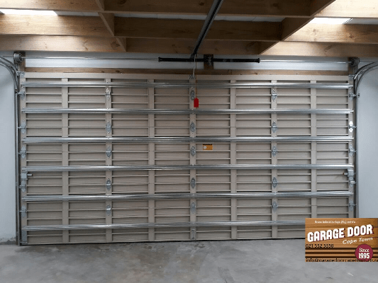 Interior view of a garage door with light tan panels and metal framing.